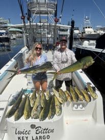 Two anglers proudly displaying their catch of Mahi Mahi on the deck of a fishing boat in Key Largo, showcasing a successful day on the water.