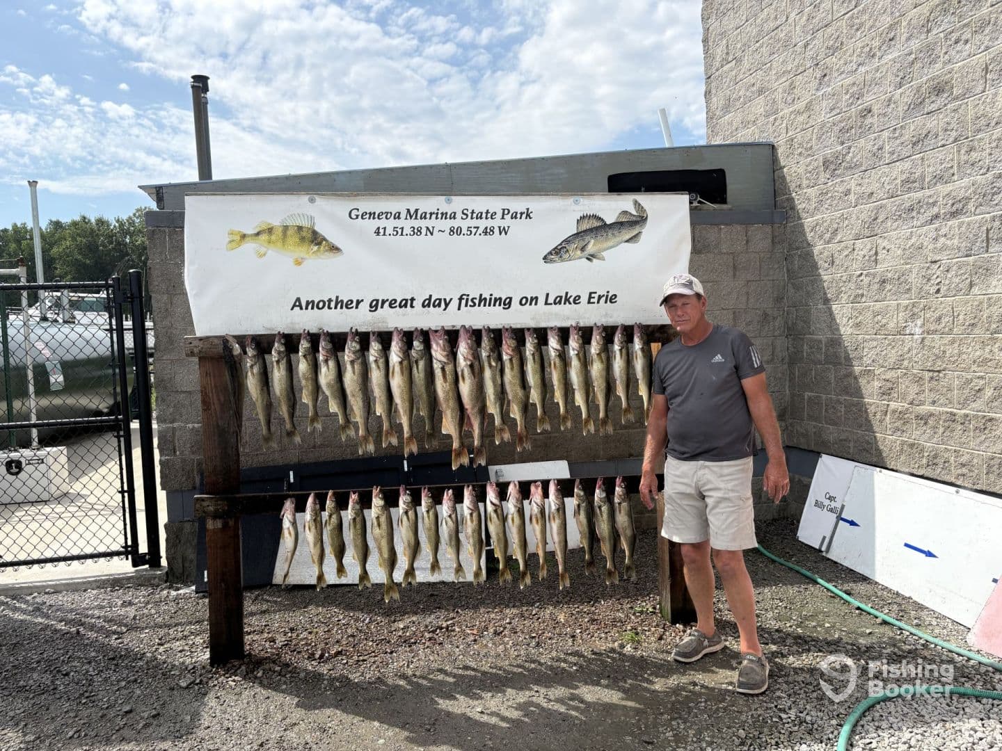 A fisherman stands proudly next to a catch board displaying numerous Walleye caught at Geneva Marina State Park on Lake Erie.