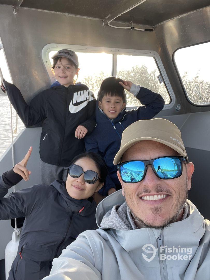A family enjoying their time on a fishing charter, with two kids and an adult posing inside the boat's cabin.