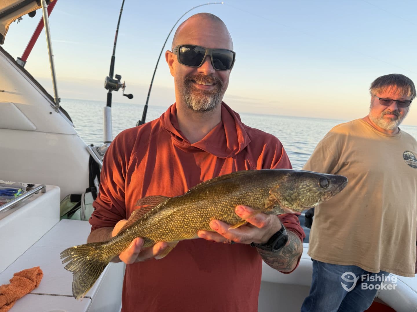Angler proudly displaying a Walleye while fishing on a boat, with calm waters in the background.