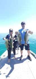Two anglers proudly displaying their catch of striped bass while on a fishing trip in clear waters.