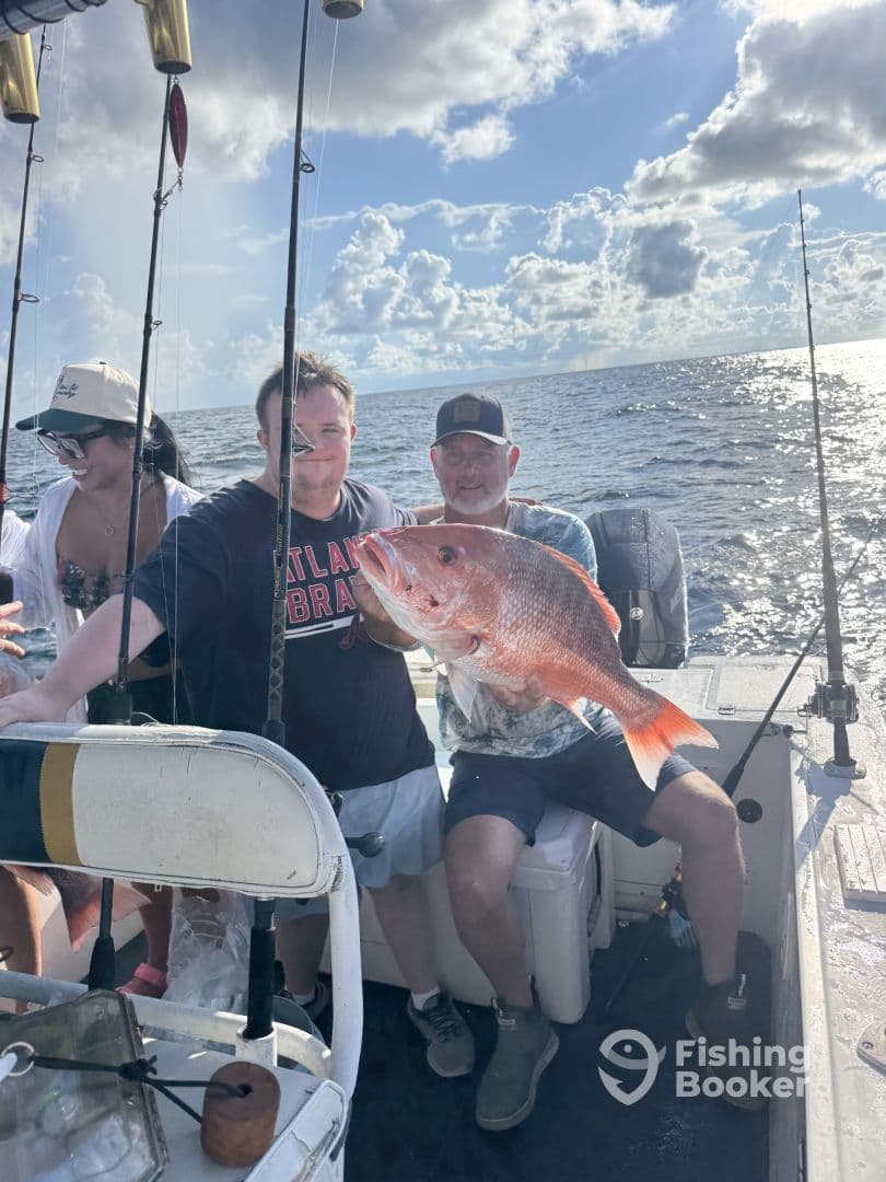 Group of anglers on a boat proudly displaying a large Red Snapper caught during a deep-sea fishing trip.