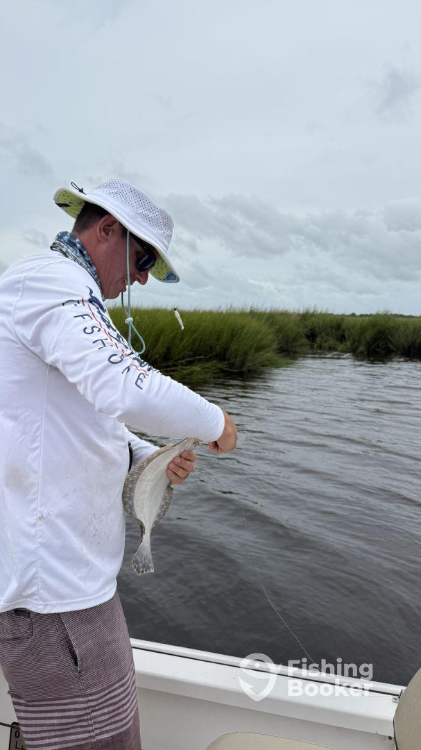 Angler reeling in a fish while fishing in a scenic marsh environment, showcasing the excitement of the catch.