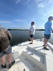 Three anglers actively fishing from a boat in a scenic waterway, showcasing a relaxed fishing environment.