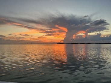 A stunning sunset over calm waters, reflecting vibrant colors, creating a picturesque fishing environment.