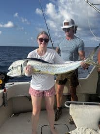 A proud angler displaying a large Mahi Mahi on a fishing boat, enjoying a successful day out on the water.