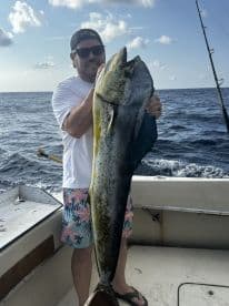 Angler proudly displaying a large Mahi Mahi while fishing offshore, showcasing the excitement of a successful catch.