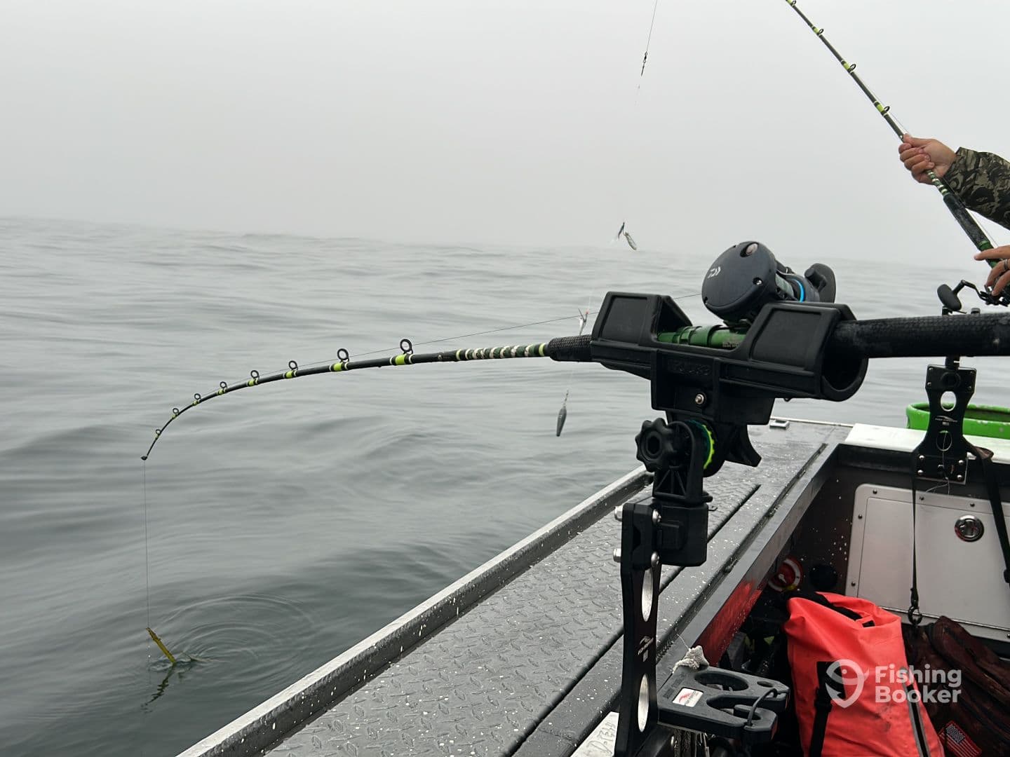 A fishing rod is bent as a fish is being reeled in during a foggy day on the water, showcasing the excitement of the catch.