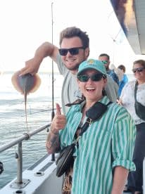 Two excited anglers displaying a caught stingray on a fishing charter, enjoying a day out on the water.