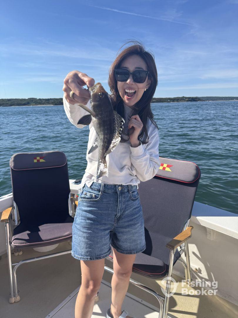 An excited angler proudly displaying a Black Sea Bass while fishing on a sunny day, showcasing a vibrant marine environment.