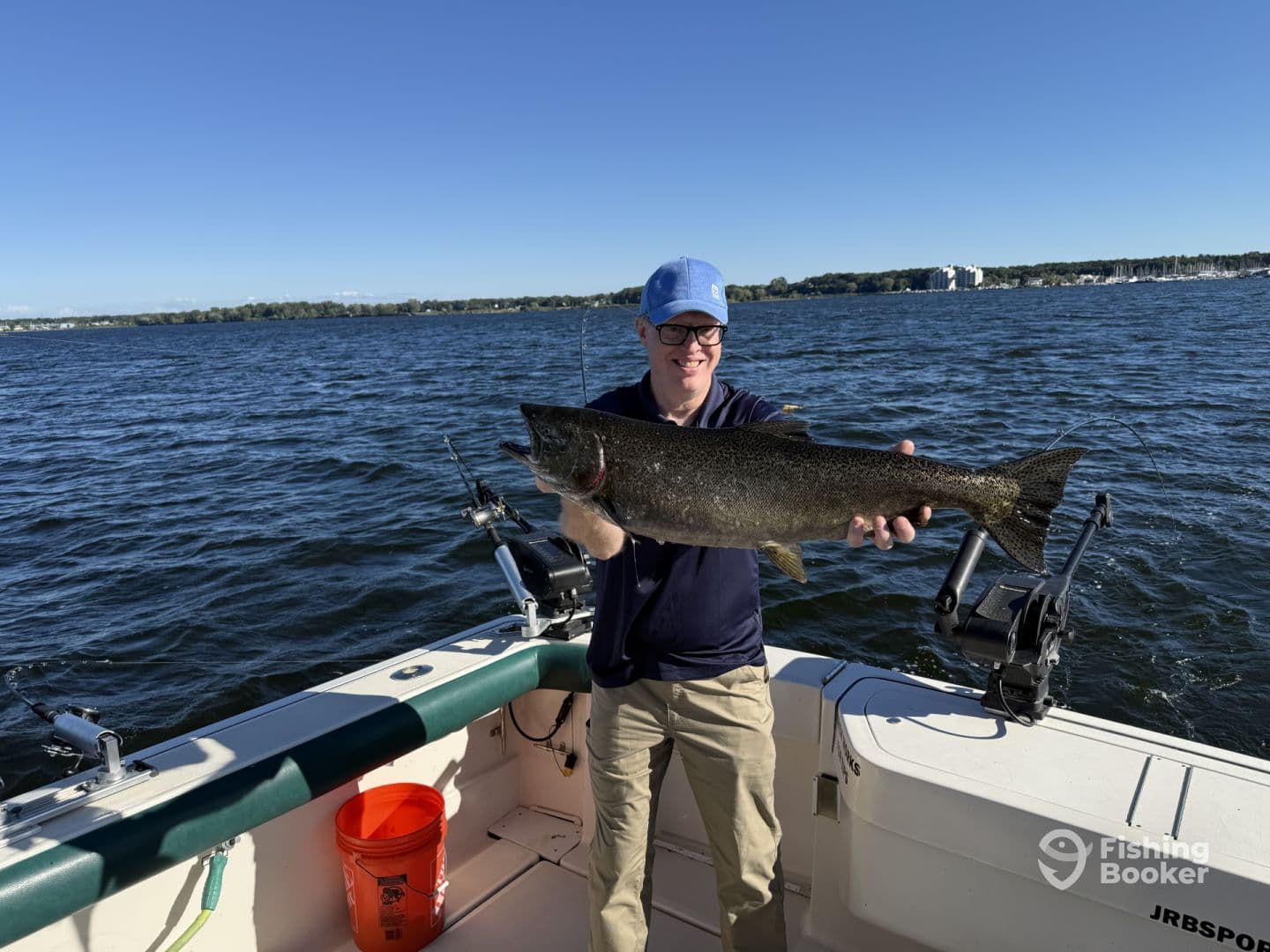 An angler proudly displaying a large Walleye while fishing on a lake, showcasing a beautiful day on the water.