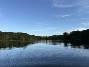 Scenic view of a calm river surrounded by lush greenery, ideal for a peaceful fishing experience.