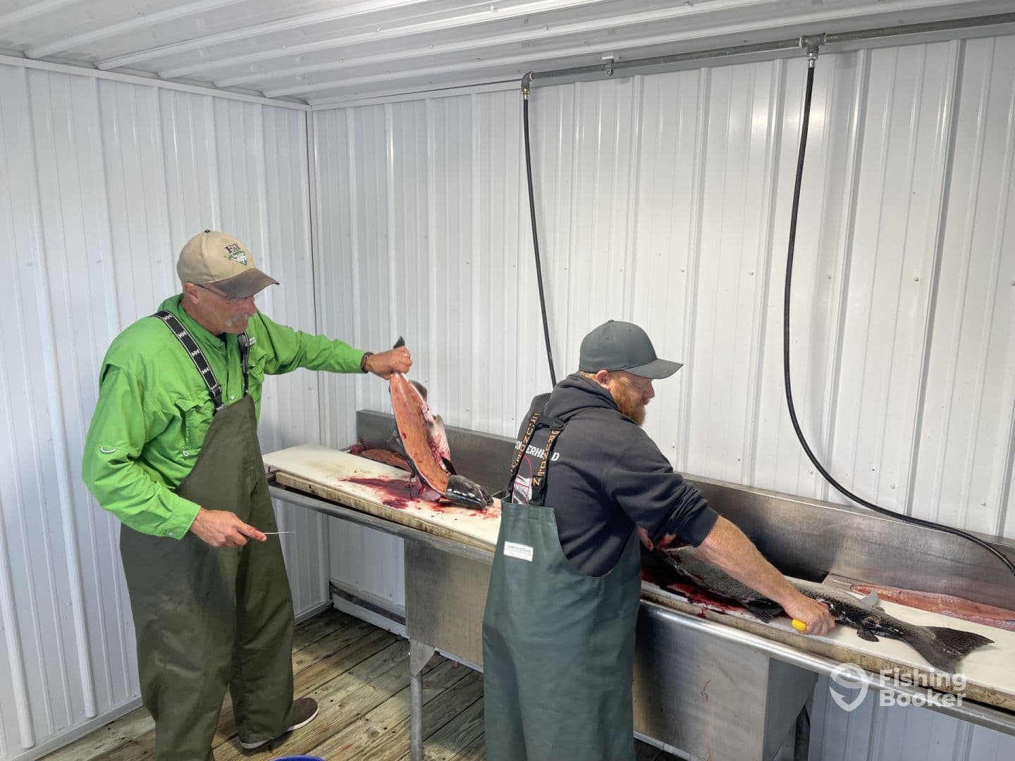 Two anglers preparing freshly caught fish at a cleaning station, showcasing their catch in a well-equipped filleting area.