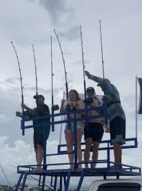 A group of anglers on a fishing platform, actively engaged in fishing with multiple rods, showcasing a lively fishing environment.