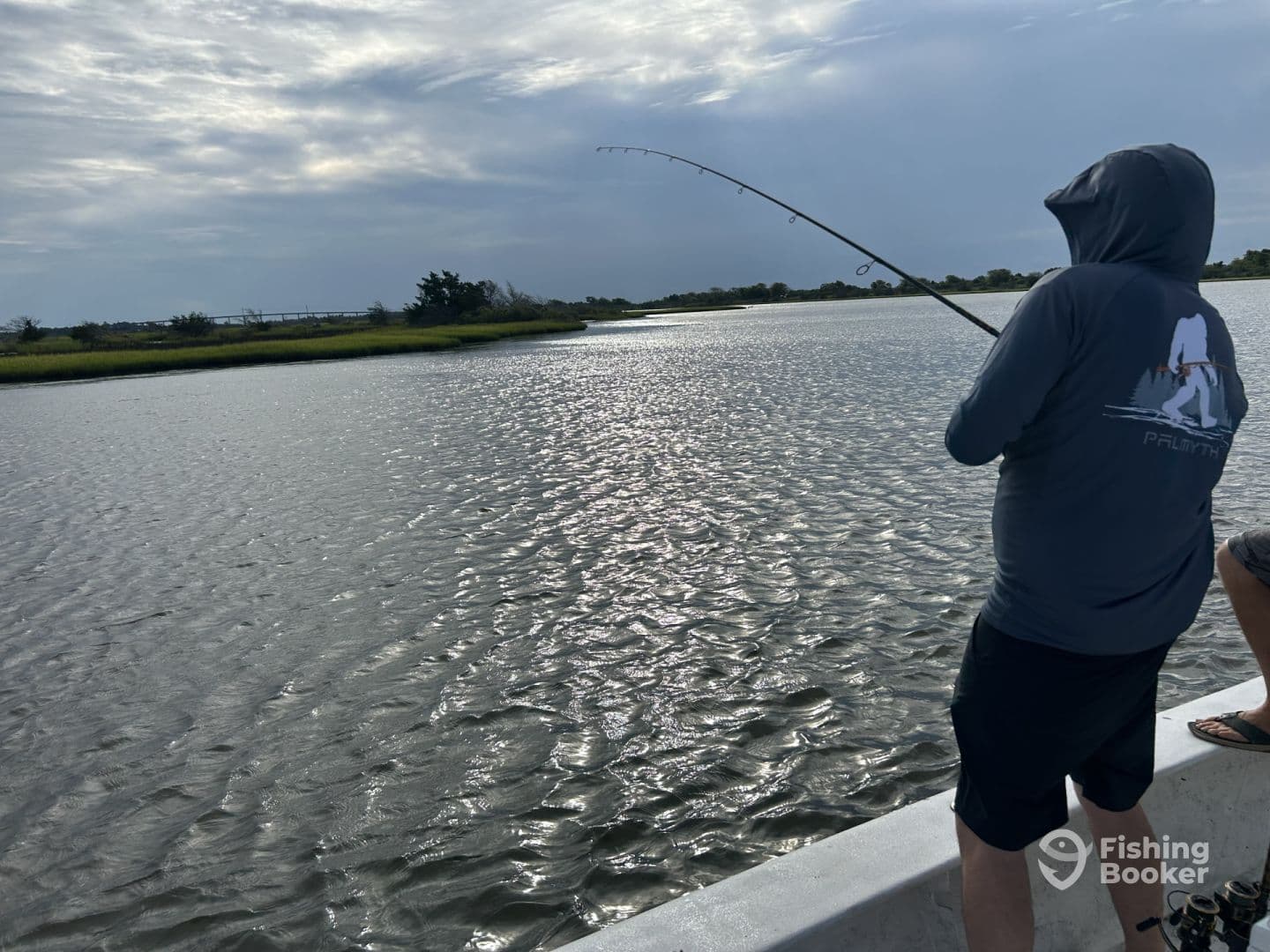 Angler reeling in a catch while fishing in a scenic coastal environment, showcasing the excitement of the sport.