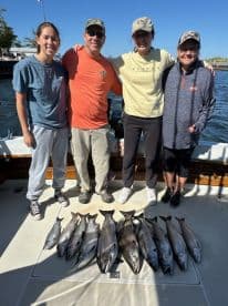 A family poses proudly with their catch of salmon on a fishing charter, showcasing a successful day on the water.