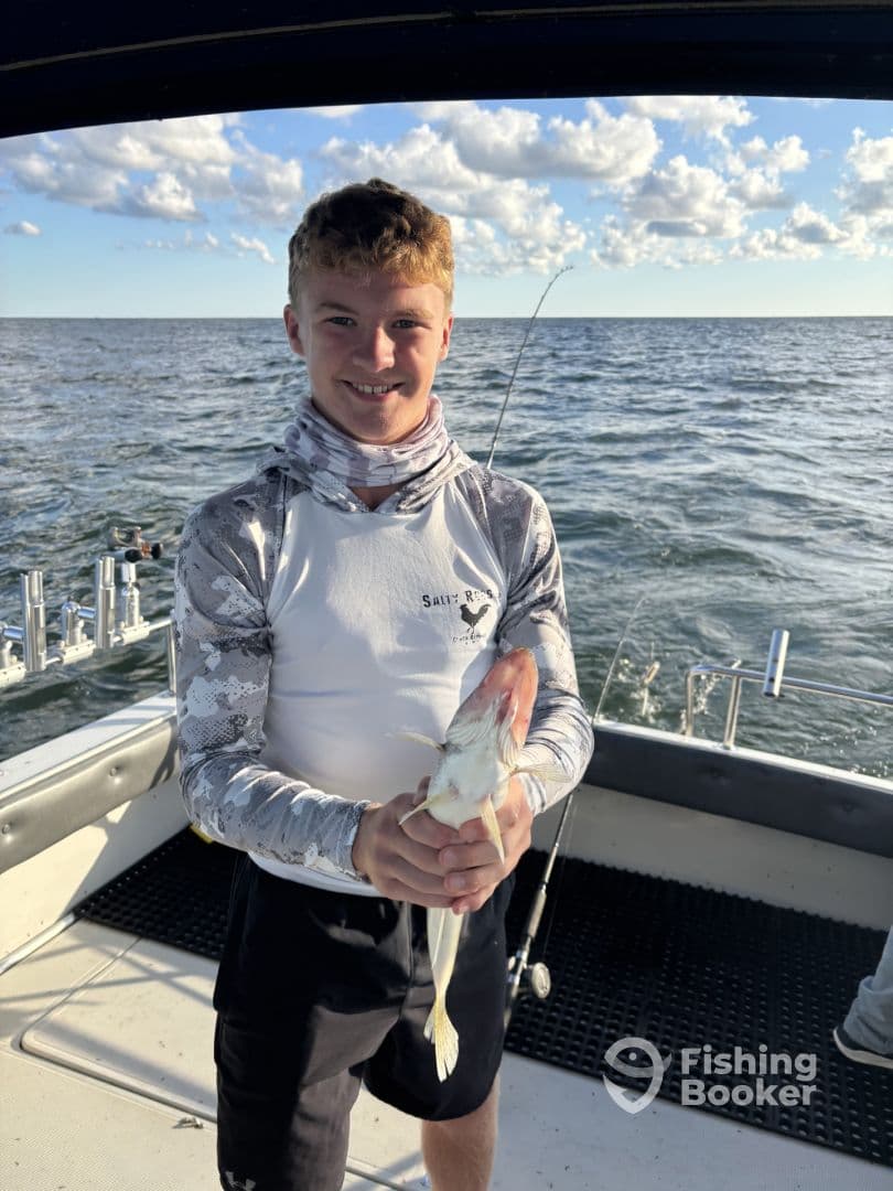 A young angler proudly displaying a caught fish aboard a fishing boat, enjoying a day on the water.