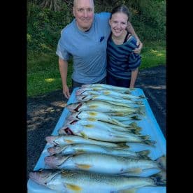 A proud duo displaying a successful catch of Walleye on a table after a fishing trip.
