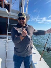 An angler proudly displaying a caught fish while aboard a fishing charter, enjoying a sunny day on the water.
