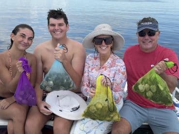 A family proudly displaying their catch of clams while enjoying a day on the water, showcasing a fun and engaging fishing experience.