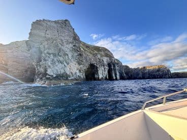 Scenic view of rugged cliffs and rock formations while cruising on a boat, showcasing the beautiful coastal landscape.