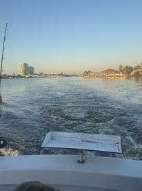 View from the boat showing a scenic waterway with buildings in the background, highlighting the boat's exterior and fishing environment.