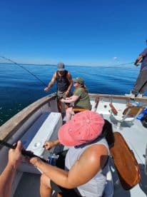 Group of anglers actively fishing on a boat, enjoying a sunny day on calm waters.