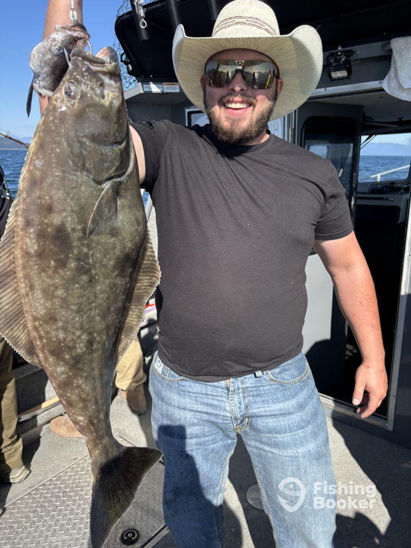 An angler proudly displaying a large Halibut aboard a fishing charter, showcasing a successful day on the water.