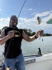 An enthusiastic angler proudly displaying a freshly caught fish while fishing on a scenic waterway.