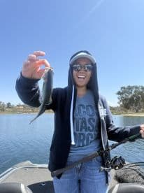 An enthusiastic angler proudly displaying a freshly caught fish while fishing on a serene lake, showcasing a fun day on the water.