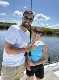 Two anglers proudly displaying a Redfish while enjoying a sunny day on the water.