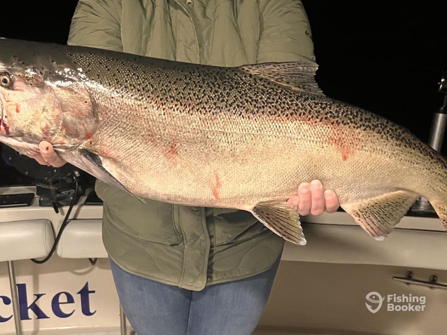Angler proudly displaying a large Trout caught during a night fishing trip, showcasing the excitement of a successful catch.