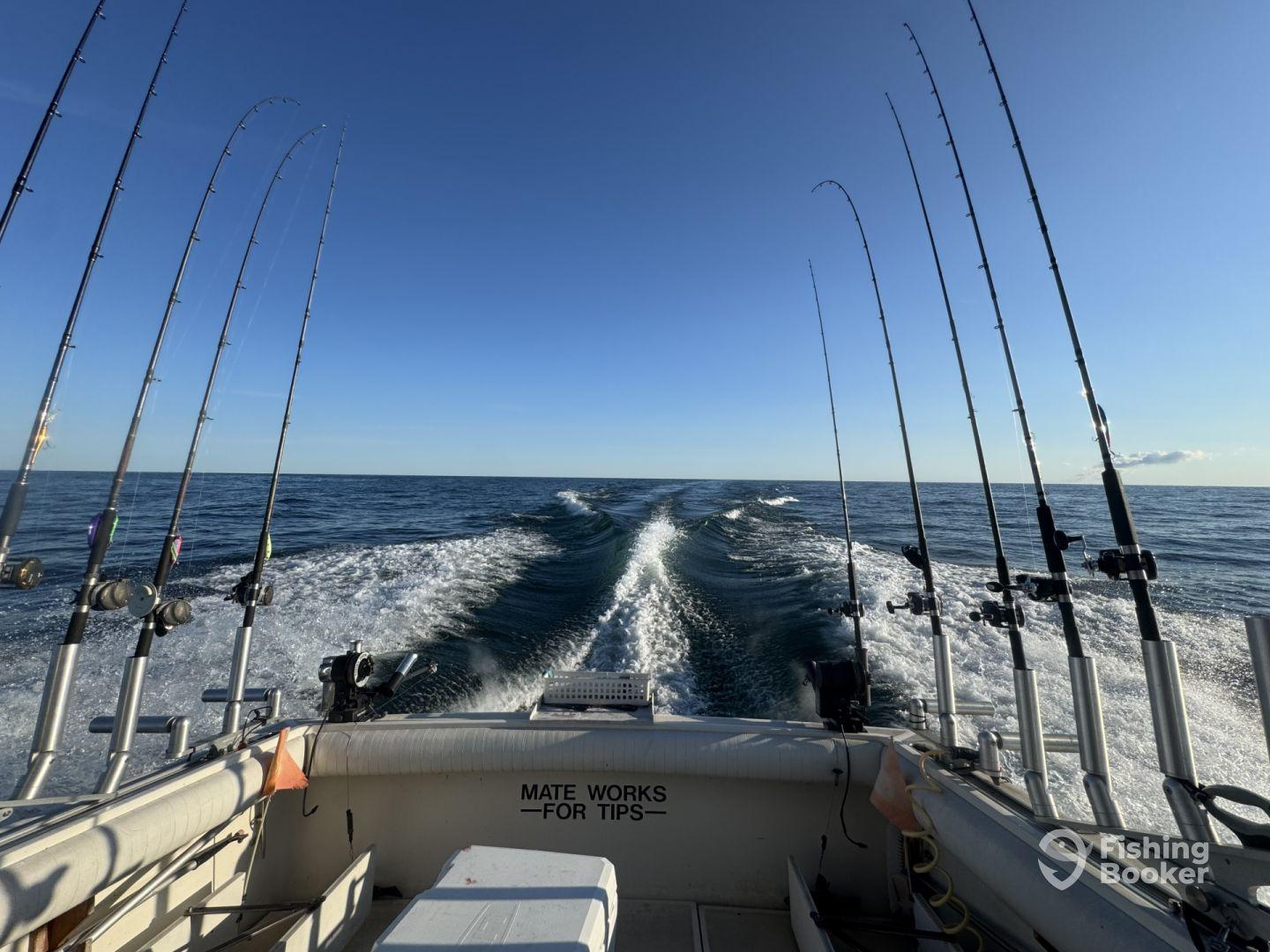 View from the boat's interior showcasing multiple fishing rods as it navigates through calm waters, ideal for deep-sea fishing.