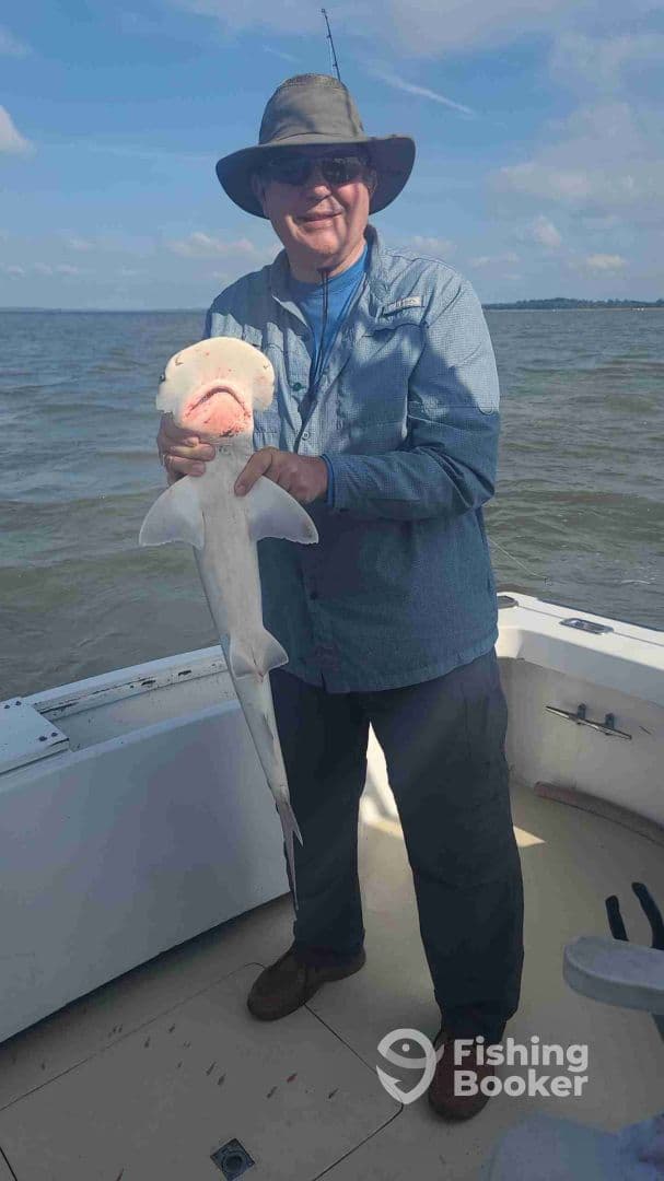 An angler proudly displaying a caught shark while on a fishing trip, showcasing the excitement of the catch.