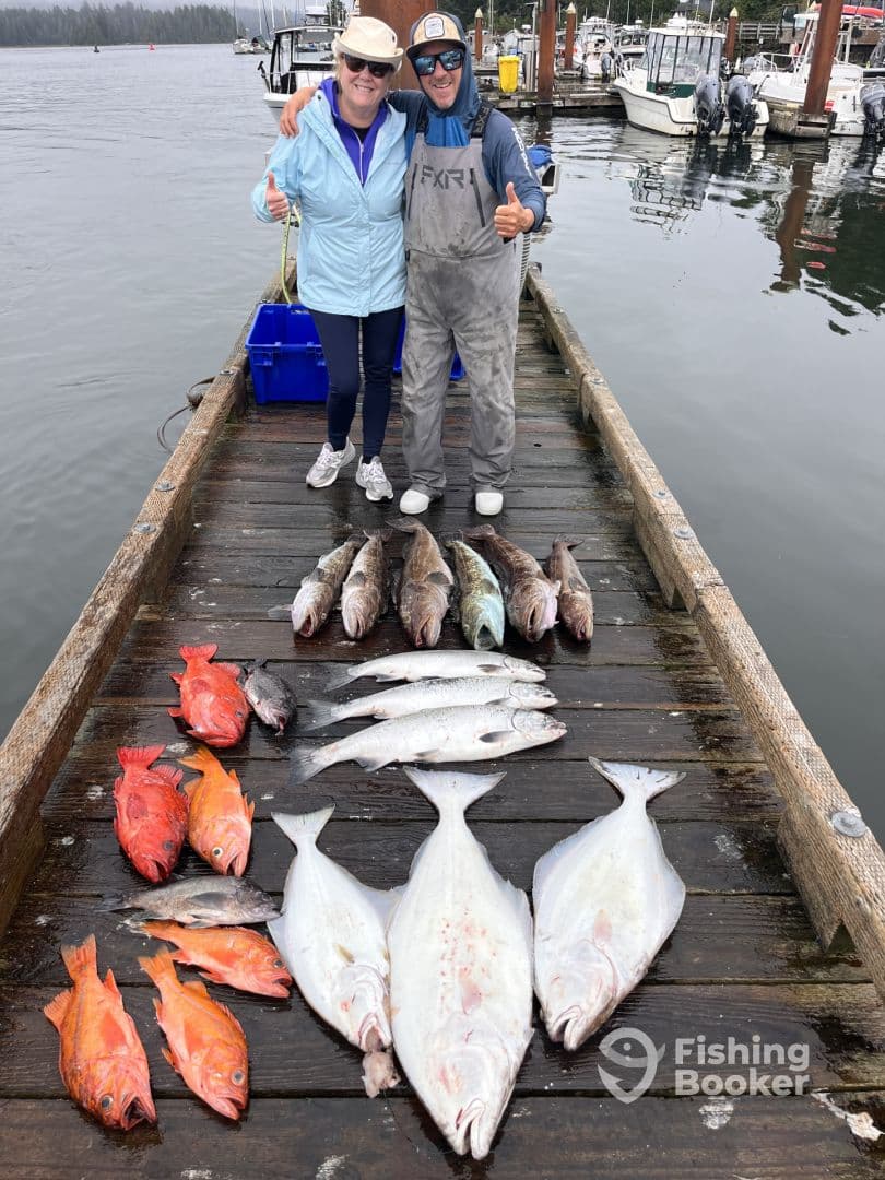 Two anglers proudly displaying a variety of fish including Halibut and Rockfish on a dock after a successful fishing trip.