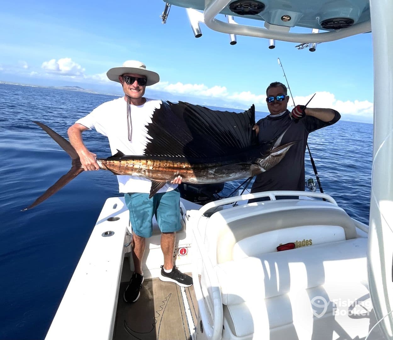 Two anglers proudly displaying a large Sailfish aboard a sport fishing boat in open waters.
