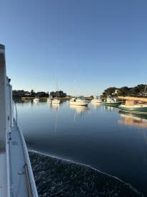 A serene view of multiple boats docked in calm waters, showcasing a clear blue sky and tranquil fishing environment.