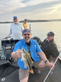A group of anglers enjoying a day on the water, with one proudly displaying a large Largemouth Bass caught during their fishing trip.