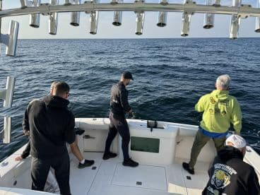 Group of anglers actively fishing on a boat, showcasing a dynamic fishing experience on open waters.