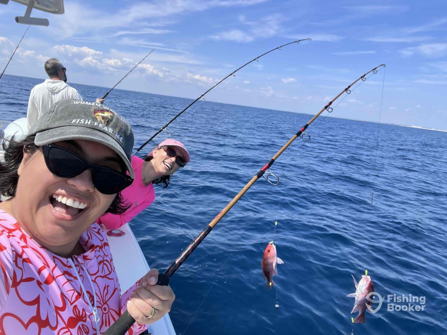 Two anglers enjoying a lively fishing experience on a sunny day, with fish visible on their lines in the open ocean.