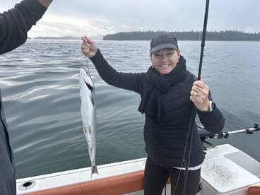 An angler proudly displaying a caught fish while fishing on a boat in a scenic coastal environment.