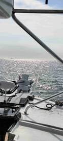 A scenic view from the side of a boat, showcasing the sparkling water and distant horizon, ideal for a day of fishing.