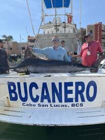 Anglers proudly displaying a large Marlin on the boat 'Bucanero' in Cabo San Lucas, showcasing a successful deep-sea fishing trip.