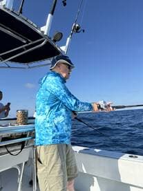 An angler actively fishing on a boat in open water, showcasing a relaxed day of sport fishing.