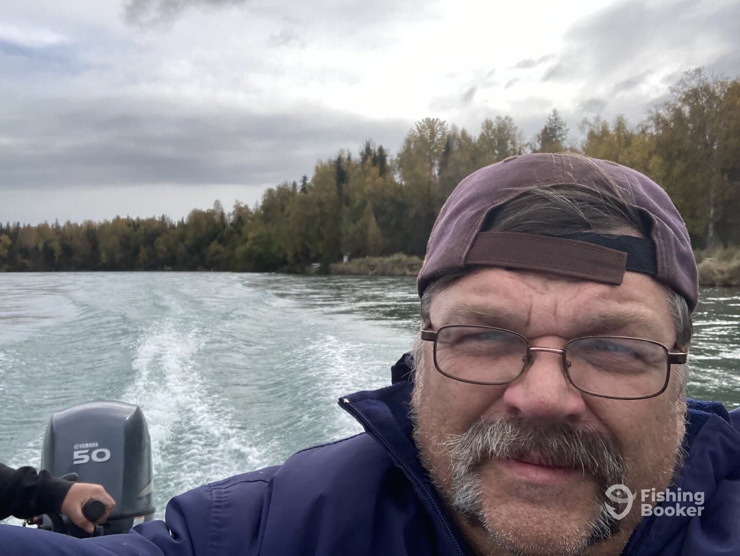 A fisherman enjoying a scenic boat ride on a river, surrounded by autumn foliage.