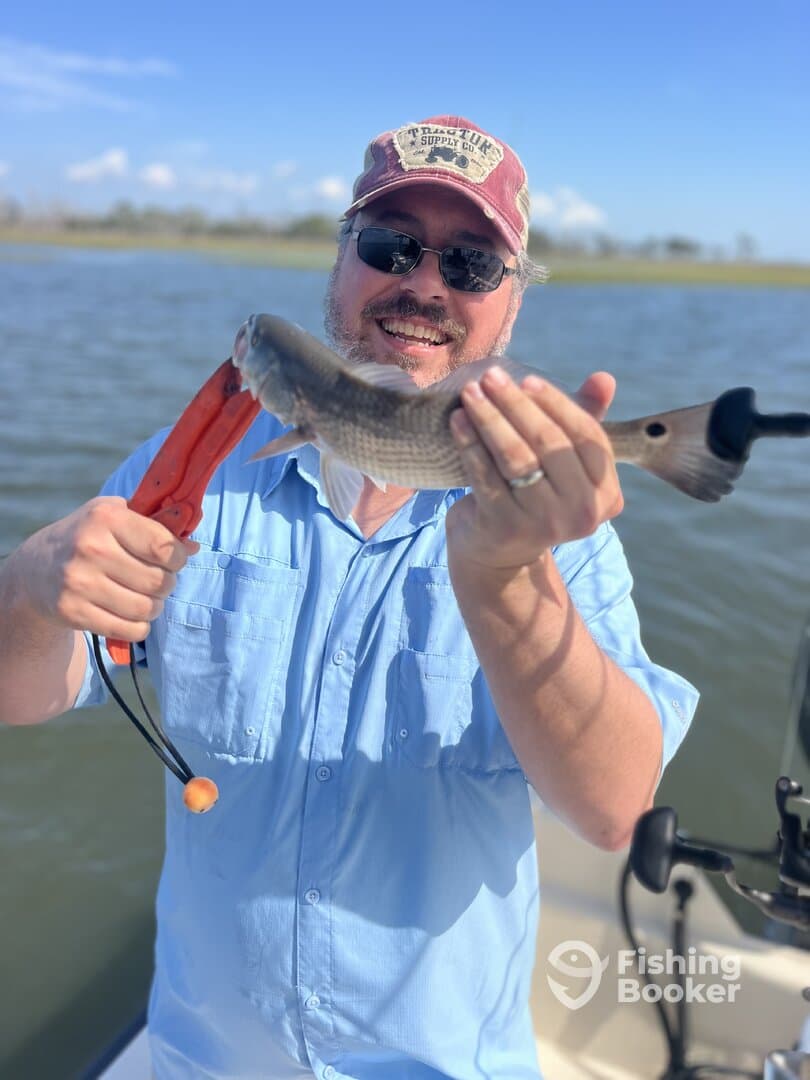 An angler proudly displaying a freshly caught fish while enjoying a day on the water, showcasing the excitement of fishing in a scenic environment.