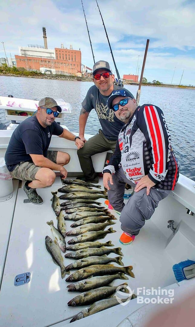 Three anglers proudly displaying a catch of multiple Walleye on the deck of their boat, showcasing a successful fishing trip.