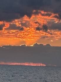 A stunning sunset over the ocean, with vibrant colors reflecting on the water, creating a serene fishing environment.