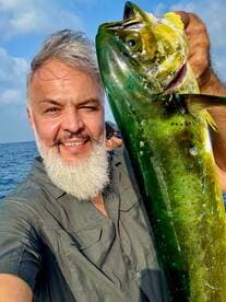 An angler proudly displaying a vibrant Mahi Mahi while fishing offshore, showcasing the excitement of a successful catch.