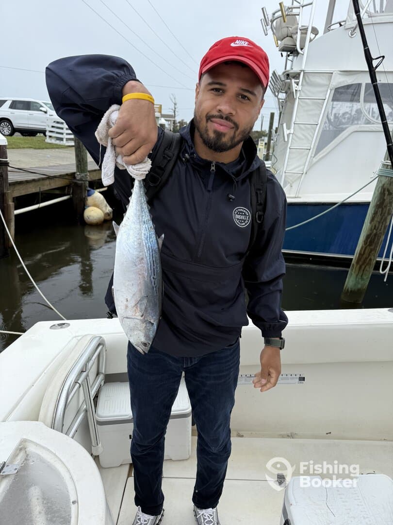 Angler proudly displaying a freshly caught fish aboard a fishing boat, showcasing a successful day on the water.